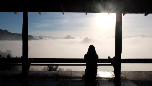 Slow motion rear view of a female traveler sitting and looking at a beautiful mountain views