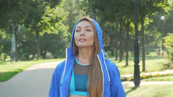 Attractive Sportswoman Taking Off the Hood Before Running in the Park