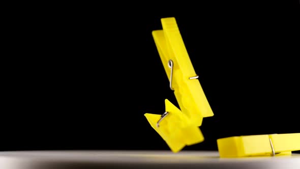 Yellow Clothespins Fall Down Onto Table Against Darkness alt