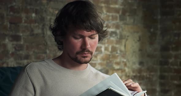 A Young Bearded Man is Carefully Reading an Interesting Book alt