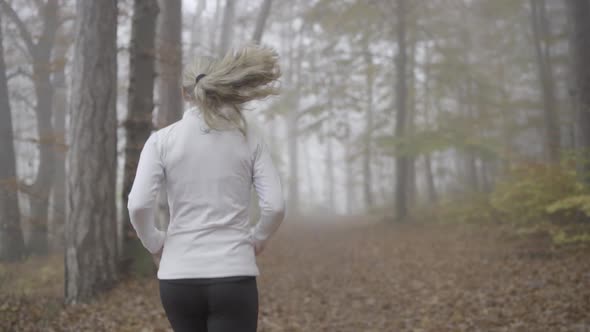 Following Jogging Woman in Foggy Forest Slow Motion