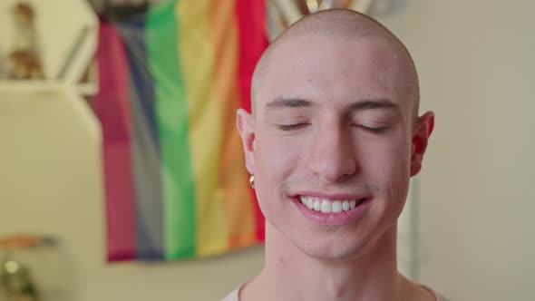 Closeup Indoor Shot of a Smiley Proud Caucasian Bald Gay Man Looking at Camera and Blinking alt