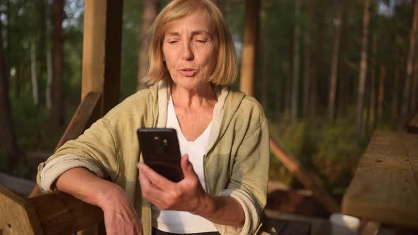 Attractive Happy Senior Elderly Woman Having Video Chat Outdoors Waving