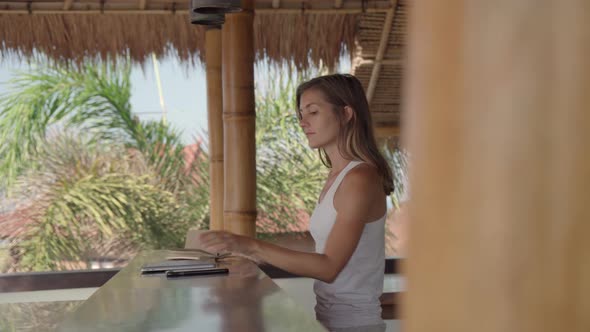 Young Woman Using Laptop and then Leaving Tropical Patio alt
