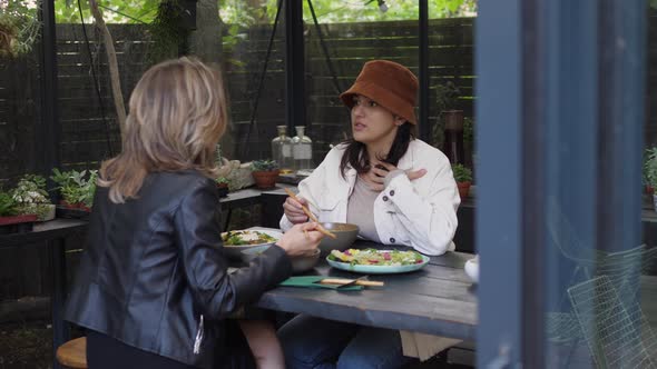 Young Woman Sharing with Her Friend Over Lunch in Hipster Café alt