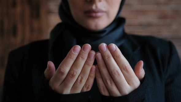 Young Serious Muslim Woman in Hijab Raises Her Hand and Prays