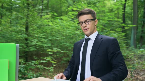 Young Satisfied Businessman Relaxing After Hardworking in Beautiful Green Park alt