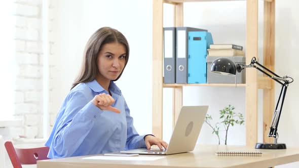 Thumbs Down Gesture by Woman at Her Work alt