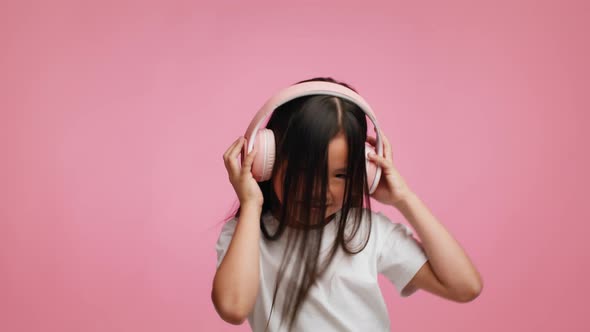 Japanese Girl Wearing Headphones Listening Music Dancing On Pink Background alt