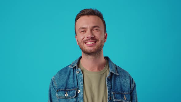 Young Caucasian Man Smiling Against Blue Studio Background
