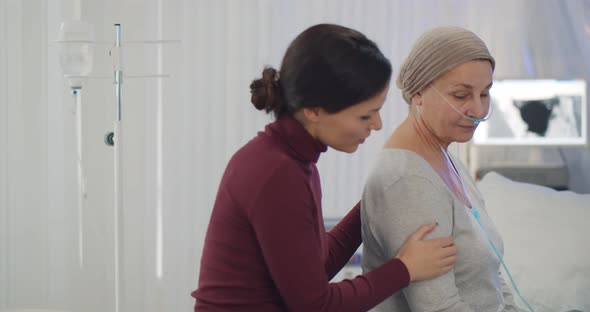Adult Daughter Hugging Sick Senior Mother with Cancer in Hospital alt