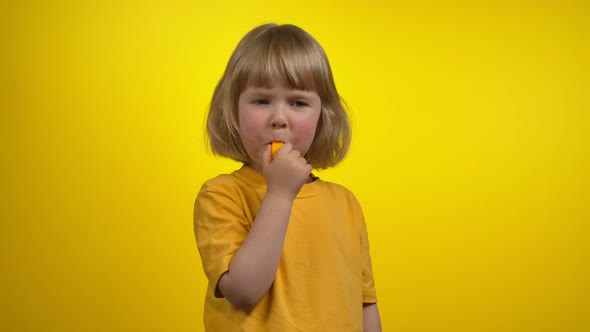 A Cute Little Girl with Short Hair is Blowing in a Whistle on a Camera alt