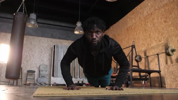 African American Man Doing Pushups in Modern Gym with Large Windows alt