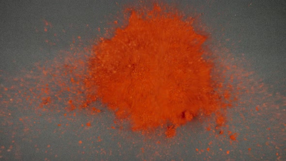 Red pepper powder falling and splashing on a black table