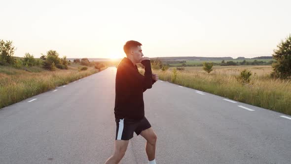 Persistent Kickboxer Training Kicks on Country Road Singly During Sunset alt