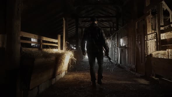 Cinematic Shot of Male Farmer Walking Through the Hay Barn to the Exit