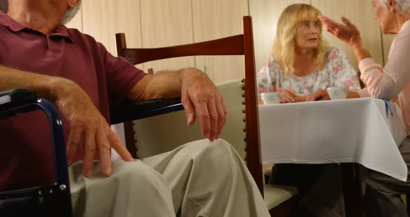 Doctor talking to senior man sitting in wheelchair alt