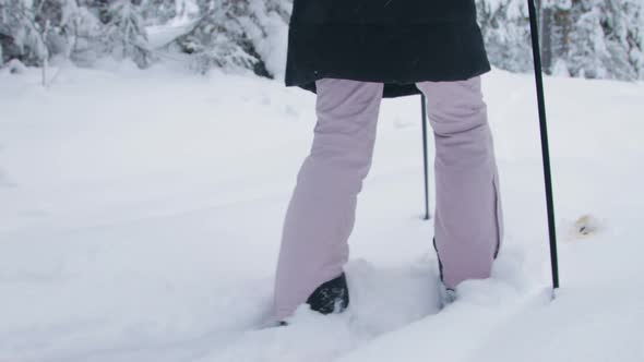 A woman walking through deep snow in forest