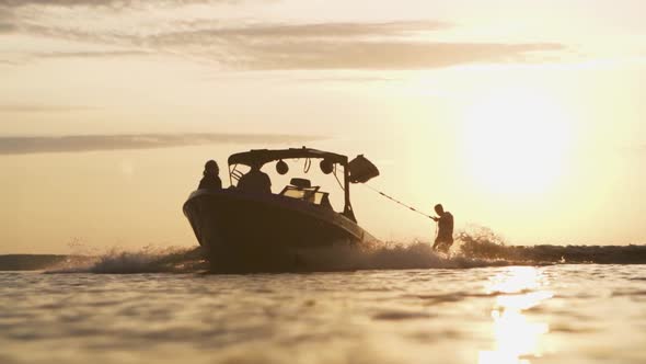 Wakeboarder Riding After Wakeboarding Boat Or Wakeboat During Sunrise
