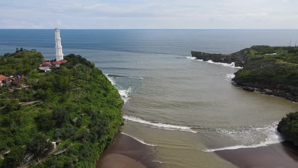 Aerial view of Baron Beach in Gunung Kidul, Indonesia with lighthouse and traditional boat. alt