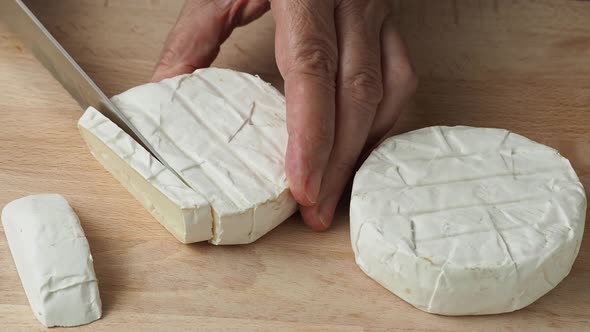 Hands cutting Camembert cheese. Farm product