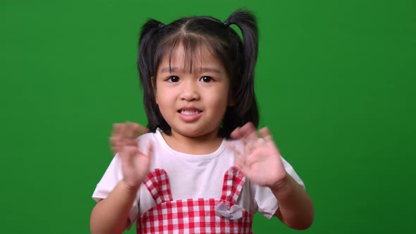 Portrait of happy Asian child girl motion to a camera on green screen background, a child looking at alt