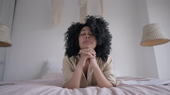 Portrait of Young Focused Woman Lying on Bed Looking at Camera Shaking Head Yes alt