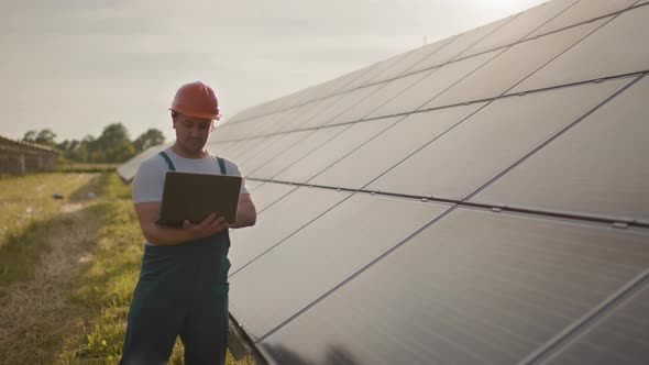 Portrait of Happy Male Engineer in Protective Helmet with a Laptop in His Hands alt