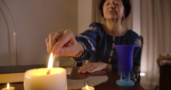 Close-up of Female Caucasian Hand Lighting Up Candle Standing at the Foreground alt