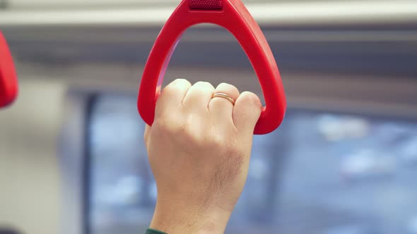 Close Up View of Male Hand Holding Looped Handle in Urban Public Transportation alt