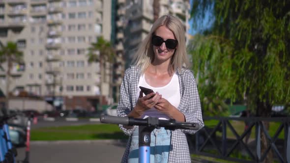 Woman unlocks electric scooter app with her smartphone. alt