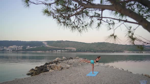 Beautiful Girl Warms Up and Practices Yoga By the Sea. Sports, Yoga, Beach.