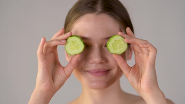 Young healthy girl with green cucumber slices
