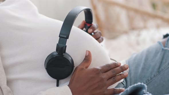 Unrecognizable African American Woman Expectant Mother Wears White Clothes Holding Headphones on alt