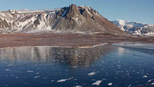 Drone Over Frozen Sea And Snow Covered Beach To Mountains alt