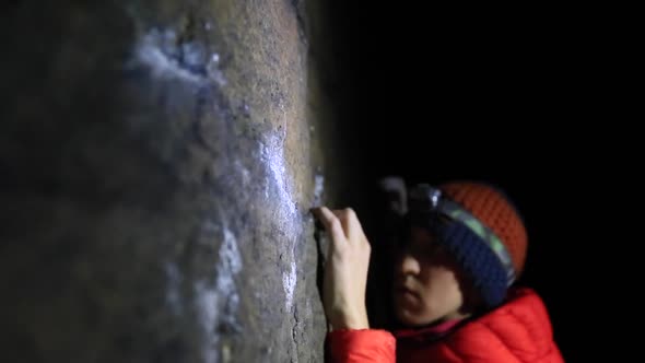Detail of a mans hands as he climbs boulders at night. alt