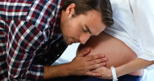Smiling man listening to pregnant womans belly in ward alt