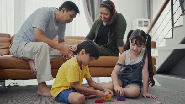 Happy family, dad and mom playing the cat on sofa, cute kids playing with blocks on floor having fun alt