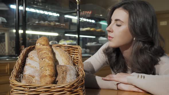 Beautiful Woman Smelling Freshly Baked Bread in a Basket at Bakery Store alt