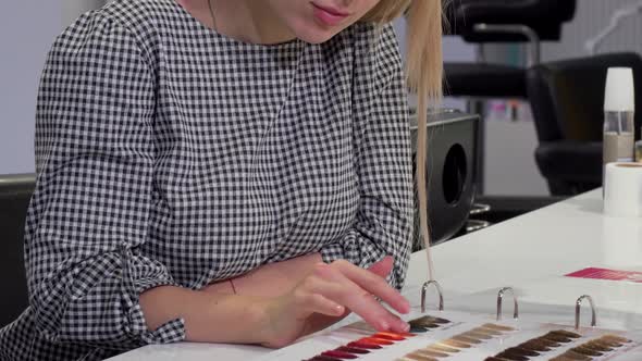 Woman Choosing Hair Color From Dye Chart at Hairdresser Salon alt