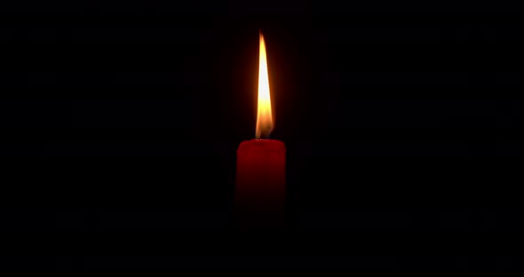 Burning red candle on a black background