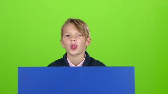 Child Boy Appeared From Behind a Blue Poster Grins Curves of Faces and Hidden Again Green Screen alt