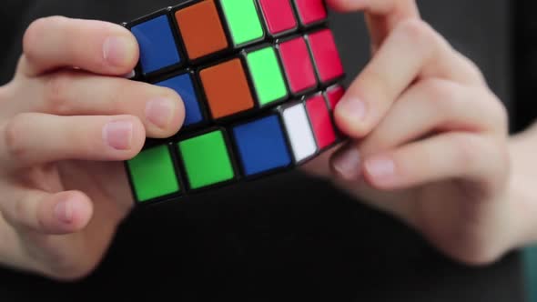 Young White Boy Solving Colourful Rubiks Puzzle Cube Black Background