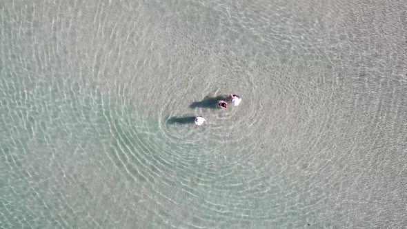 Turquoise clear water, light waves and free beach. People swim in small groups. alt