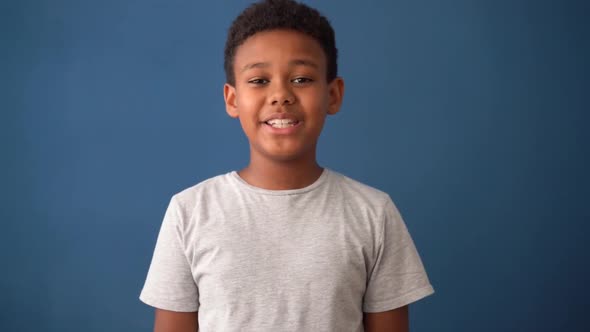 Multiracial male child showing joy and happiness. Blue background alt