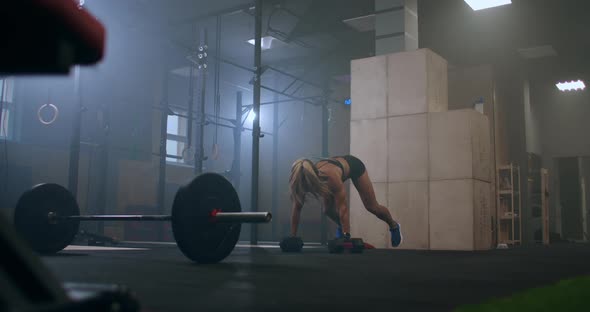 Strong Female Athlete Perform Push UPS with Dumbbells Lifting Dumbbells Over Your Head After a Jump alt