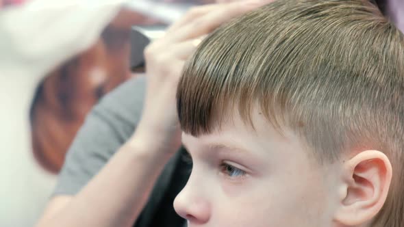 Barber Cutting Boy's Hair with Clipper in Background