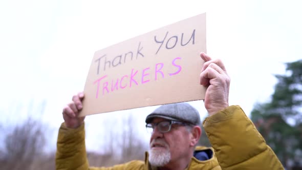 Poster with the Inscription Thank you Truckers in the Hands of an Elderly Man in Winter Clothes and alt