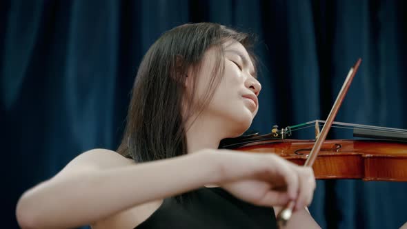 Young Asian woman playing violin at a festival party
