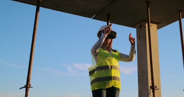 A Woman Engineer at a Construction Site in Virtual Reality Glasses Moves Her Hands Simulating the alt